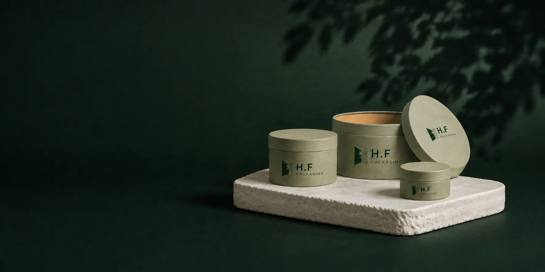 Complete sage green H.F Packaging boxes and lids against a deep forest green background